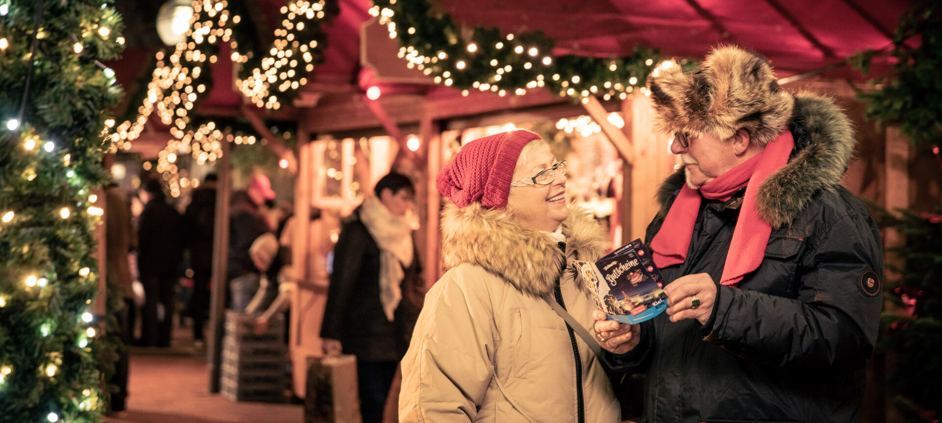 Älteres Pärchen auf dem Weihnachtsmarkt mit Gutscheinheft