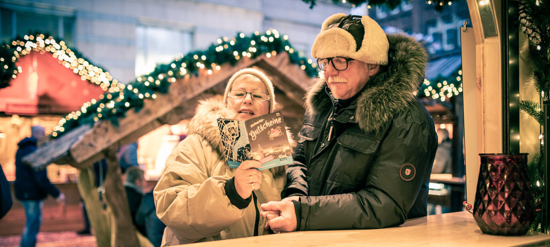 Älteres Pärchen auf dem Weihnachtsmarkt mit Gutscheinheft