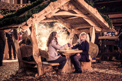 Zwei Frauen stoßen auf dem Weihnachtsmarkt mit Punschtassen an