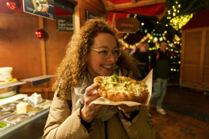Junge Frau ist Langos auf dem Weihnachtsmarkt
