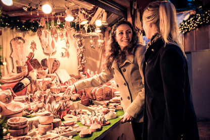 Zwei junge Frauen suchen sich Artikel an einem Weihnachtsmarktstand aus.