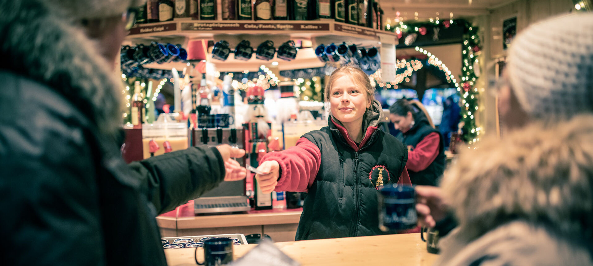 Verkäuferin beim Annehmen eines Gutscheins beim Glühweinstand auf dem Weihnachtsmarkt