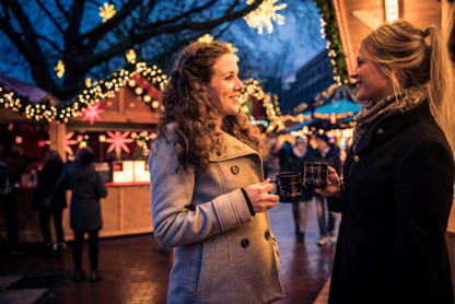 Zwei Frauen stoßen auf dem Weihnachtsmarkt mit Punschtassen an