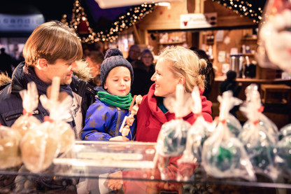 Eltern und Kind am Stand mit Süßigkeiten auf dem Weihnachtsmarkt