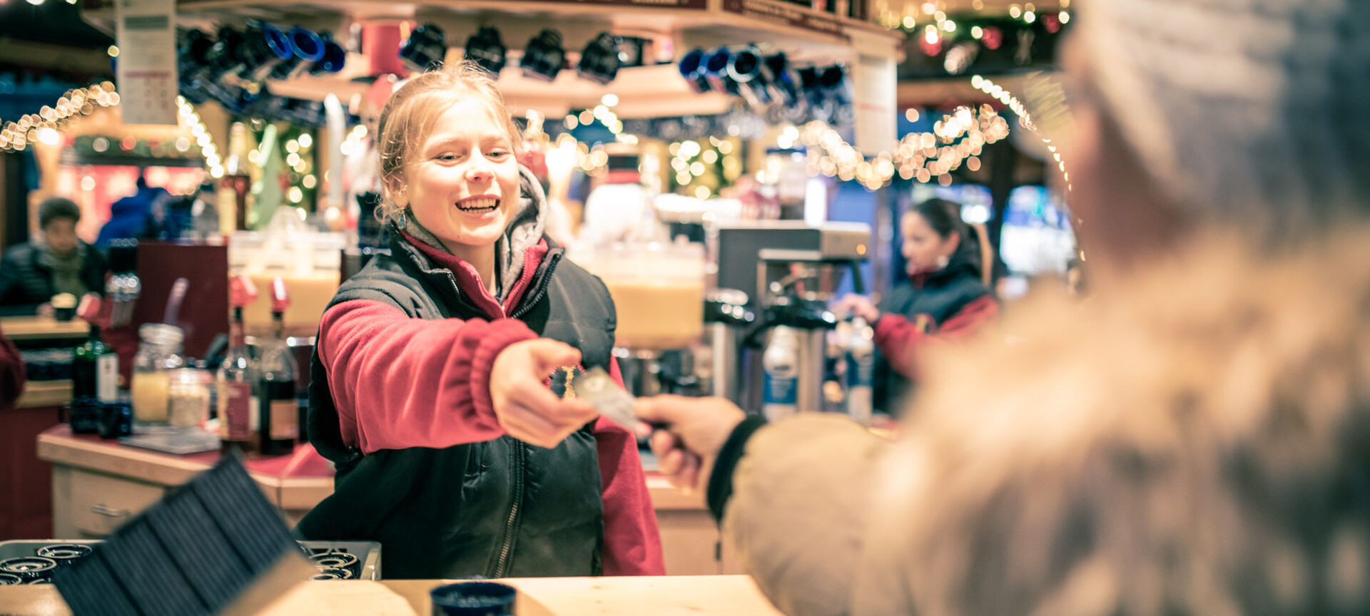 Verkäuferin nimmt lächelnd Gutschein auf dem Weihnachtsmarkt an