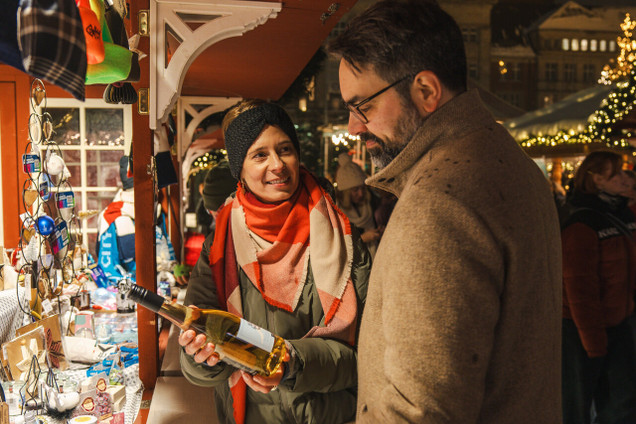 Pärchen kauft eine Flasche Kieler Wein auf dem Souvenirs-Stand auf dem Rathausplatz