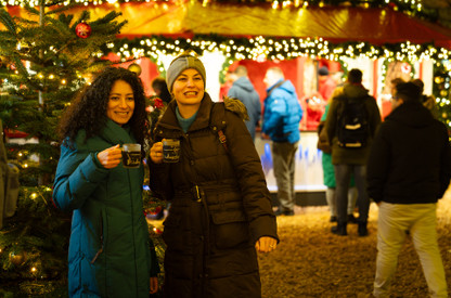 zwei junge Frauen halten Glühweintassen auf dem Weihnachtsmarkt in der Hand