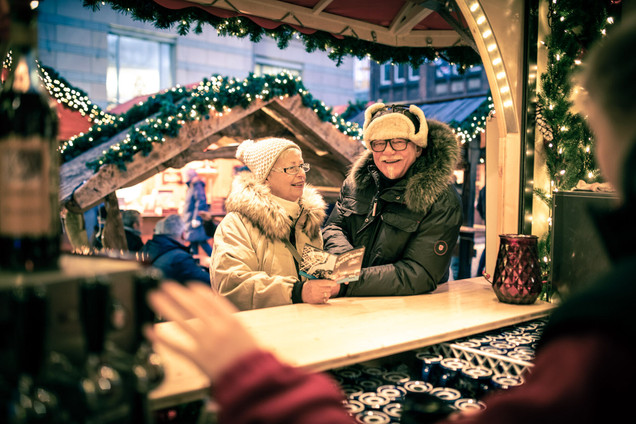 Älteres Pärchen hält das Gutscheinheft in der hand am Glühweinstand auf dem Weihnachtsmarkt